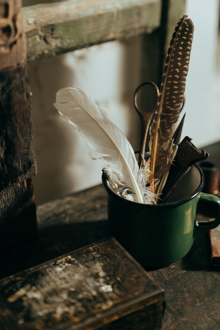 A rustic scene featuring a vintage mug filled with feathers and old tools on a wooden table.